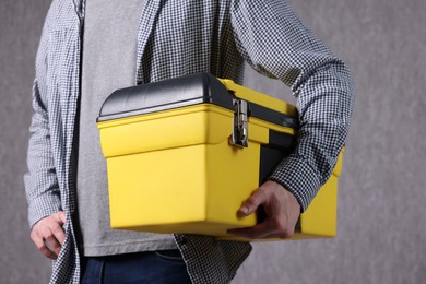 Young man with tool box on grey background, closeup