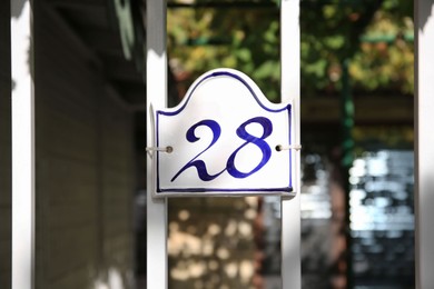 Photo of Plate with house number hanging on iron fence outdoors
