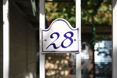 Plate with house number hanging on iron fence outdoors