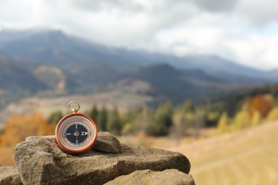 Photo of Compass on rock in mountains, space for text
