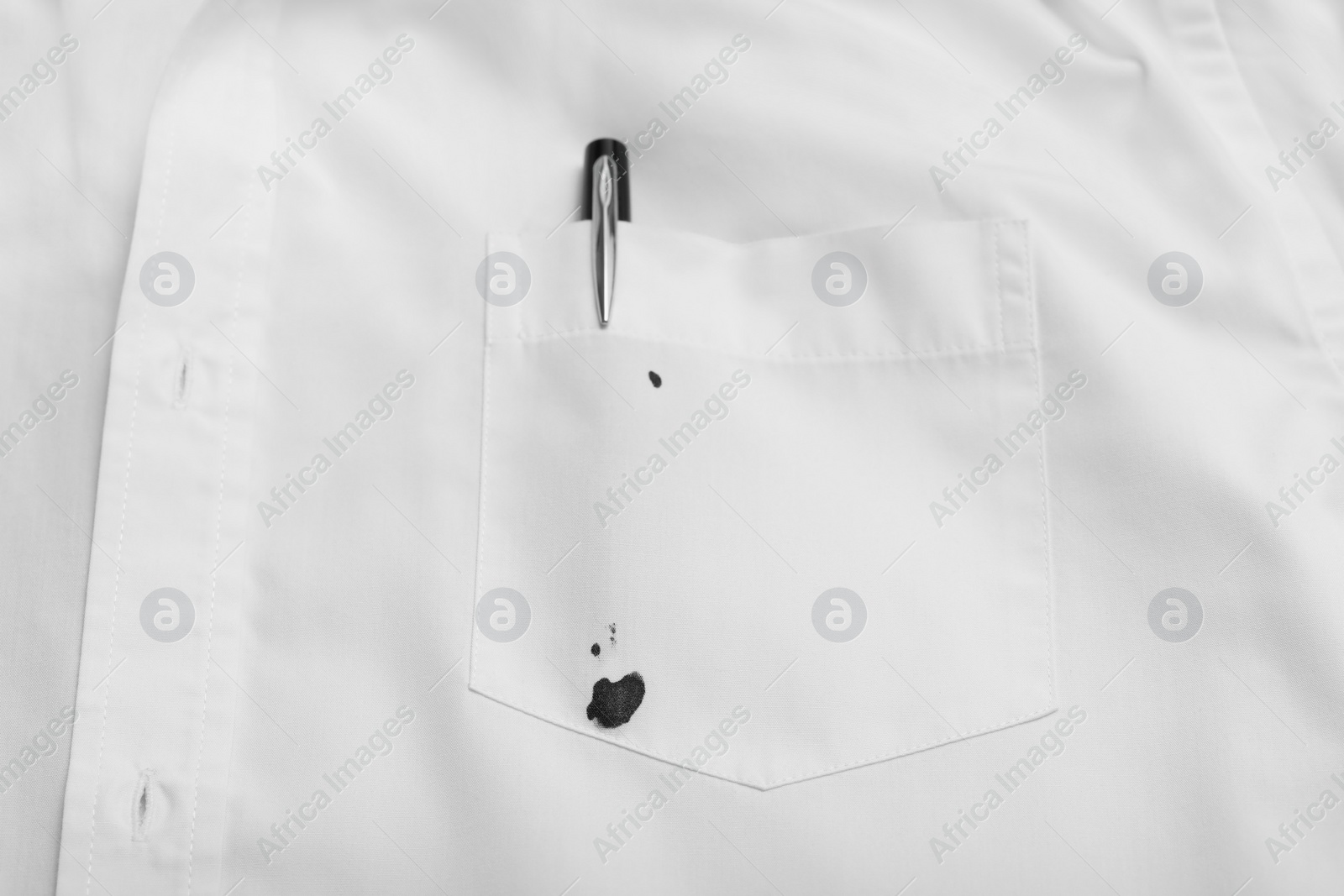 Photo of Pen and stain of black ink on white shirt, top view. Space for text