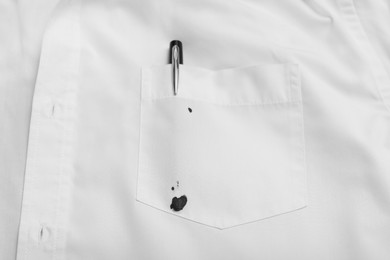 Photo of Pen and stain of black ink on white shirt, top view. Space for text