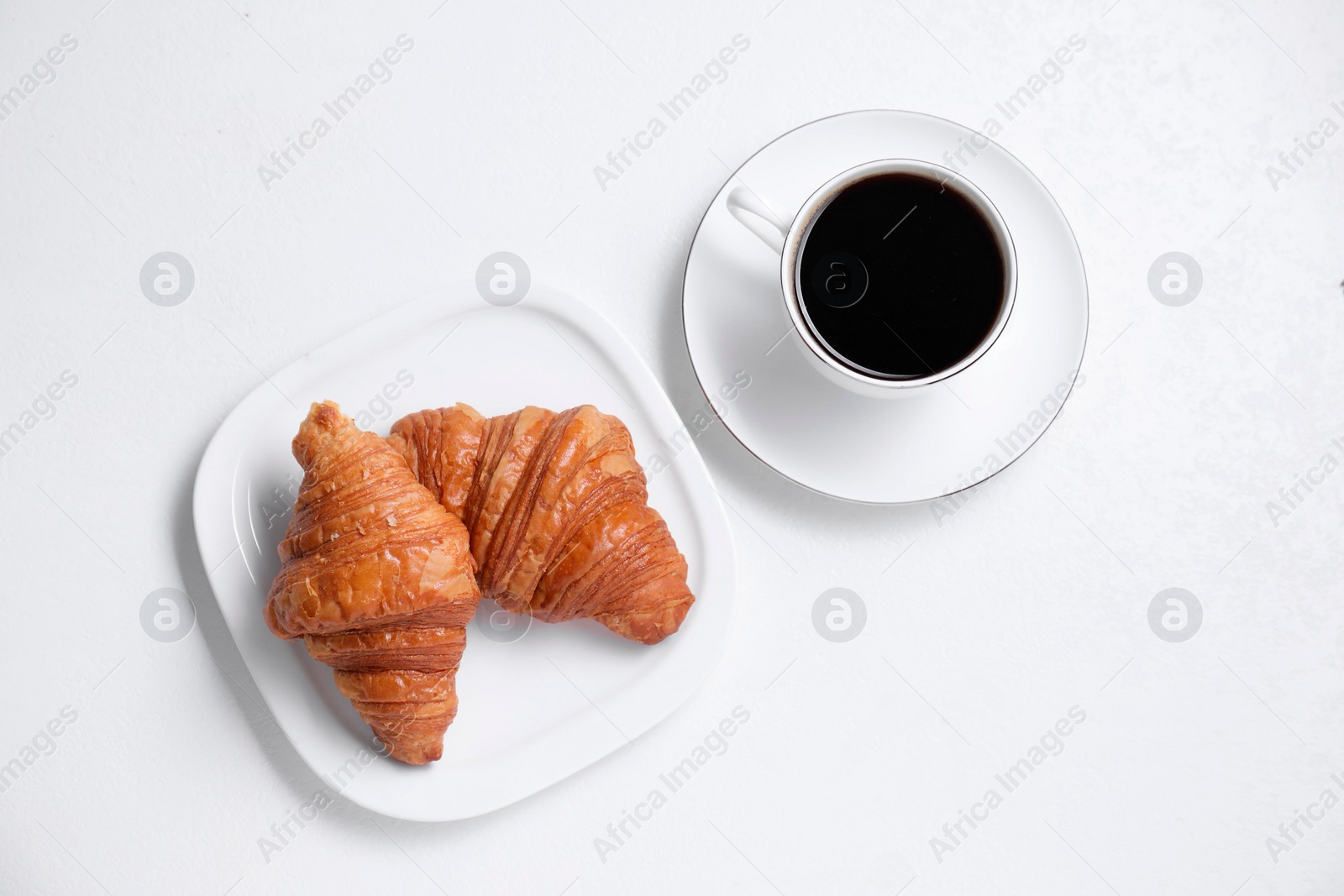 Photo of Fresh croissants and coffee on white background, flat lay. Tasty breakfast