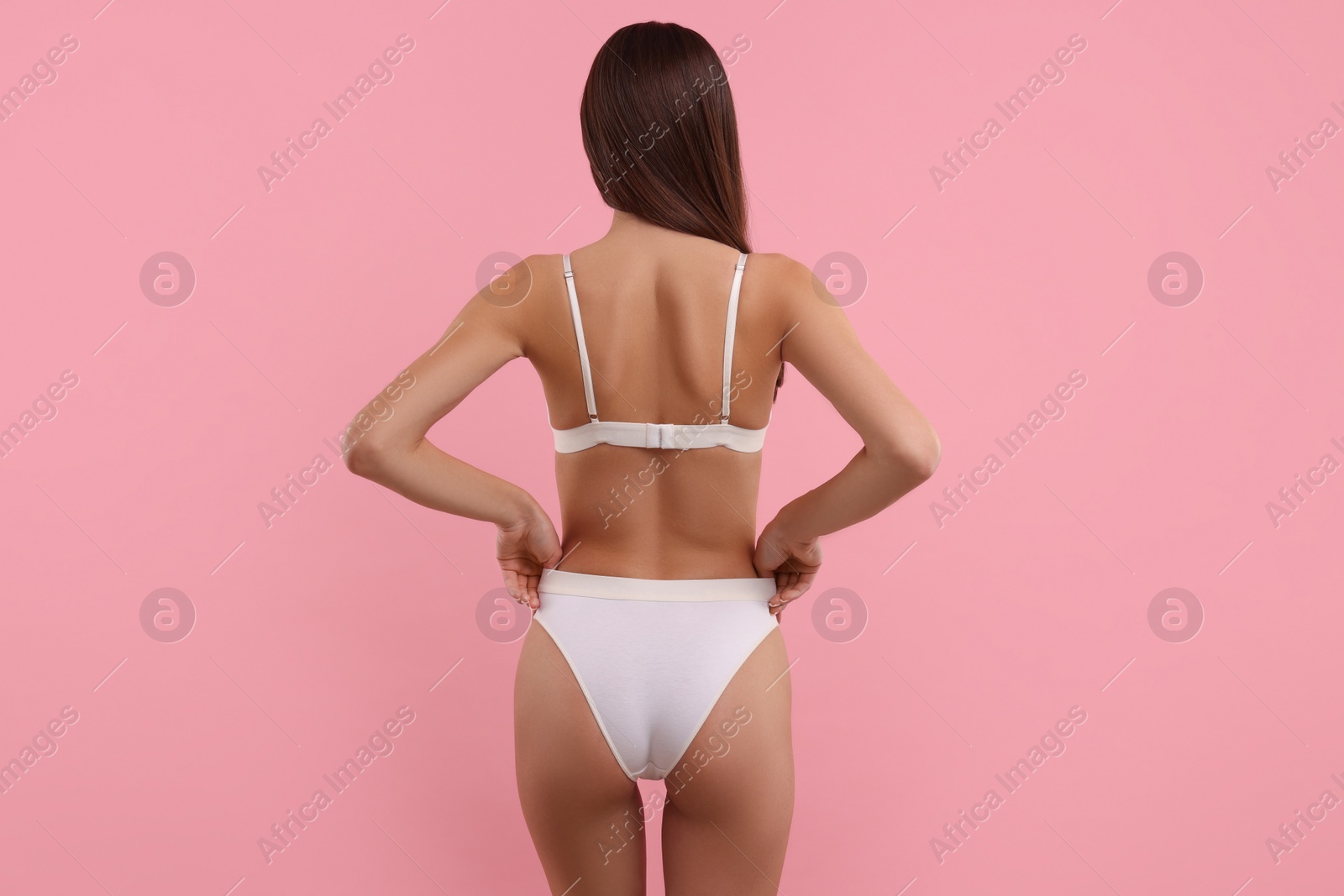 Photo of Young woman in stylish white bikini on pink background, back view