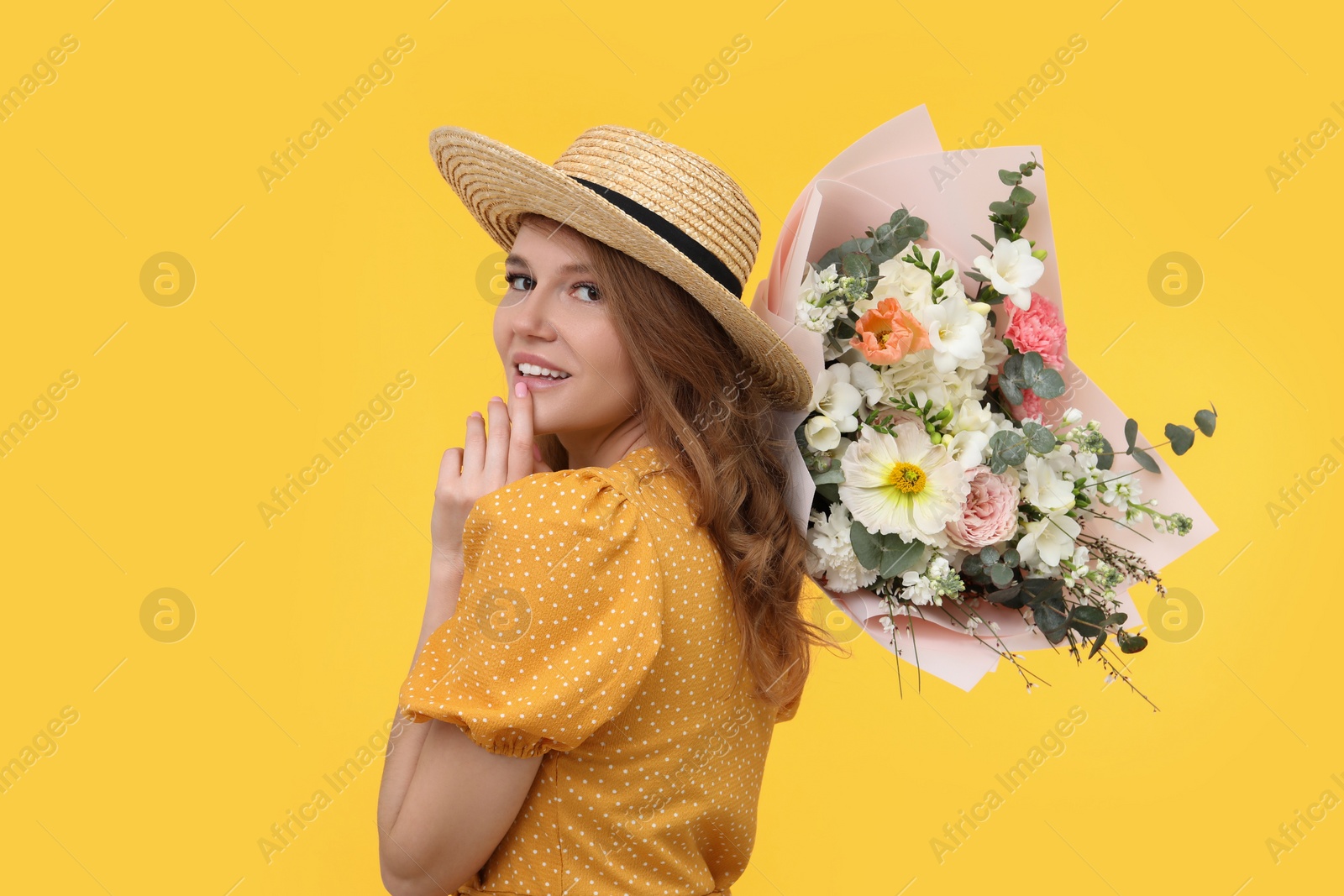 Photo of Beautiful woman in straw hat with bouquet of flowers on yellow background