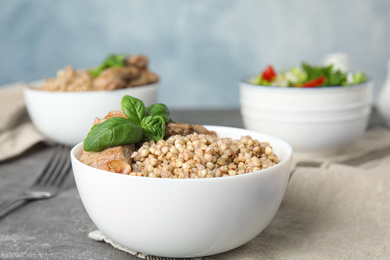 Tasty buckwheat porridge with meat on grey table