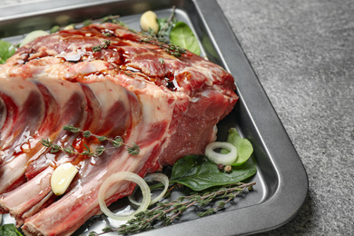 Photo of Raw spare ribs with herbs and seasonings on grey table, closeup