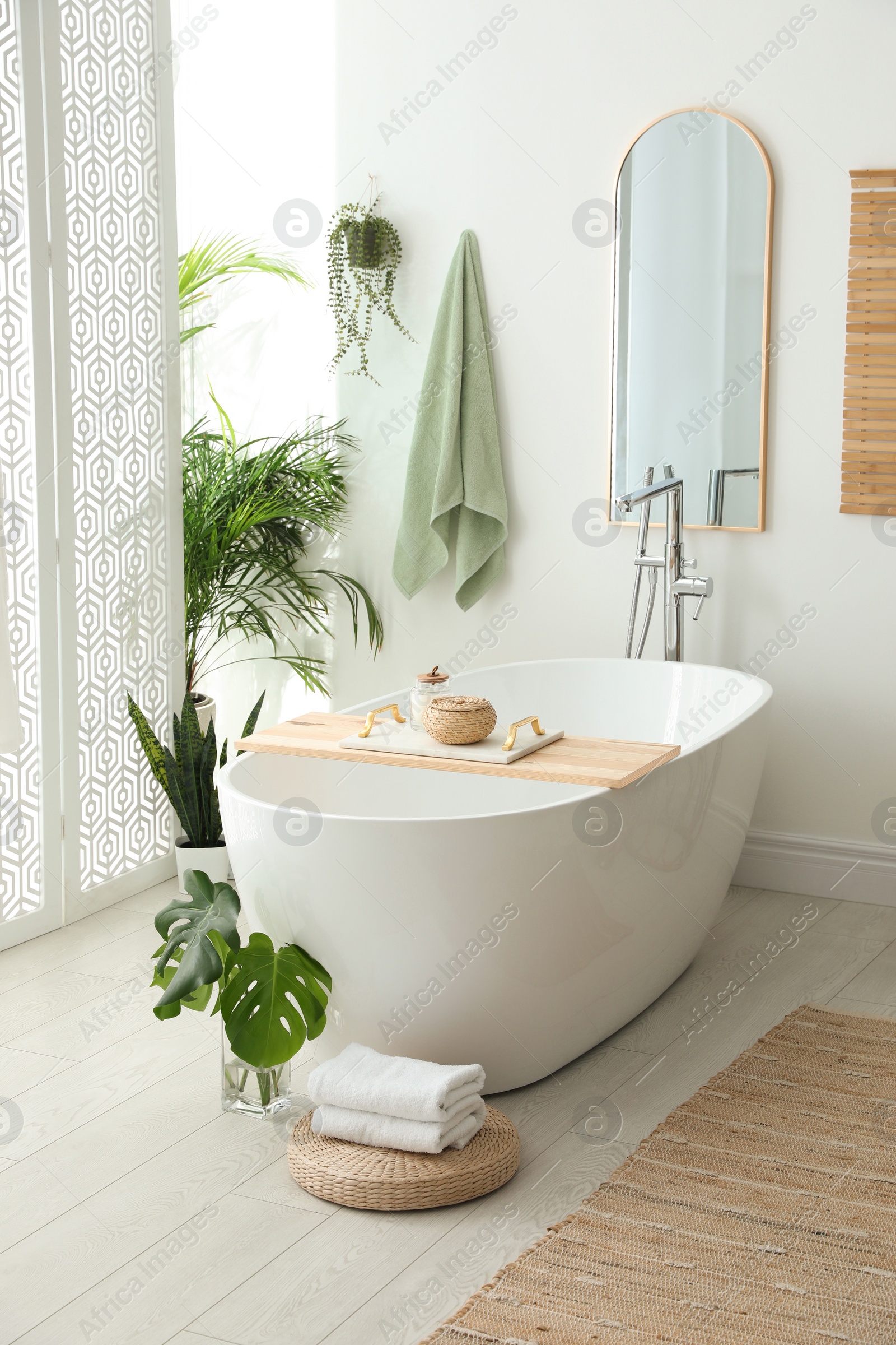 Photo of Stylish bathroom interior with modern tub, houseplants and beautiful decor. Home design