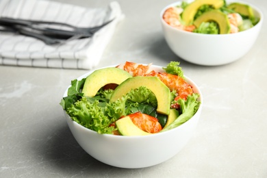 Delicious avocado salad with shrimps in bowl on grey marble table