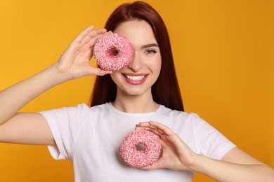Photo of Happy woman with red dyed hair and donuts on orange background