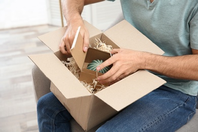 Young man opening parcel at home, closeup