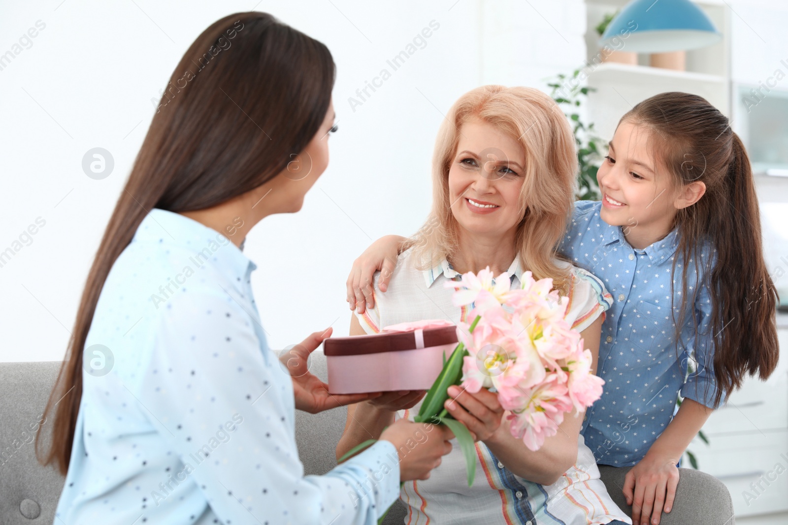 Photo of Woman and her daughter congratulating granny at home. Happy Mother's Day