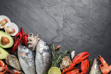 Photo of Fresh fish and different seafood on black table, flat lay. Space for text