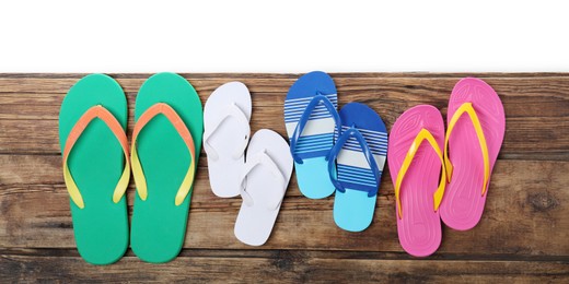 Photo of Different stylish flip flops on wooden table against white background, top view