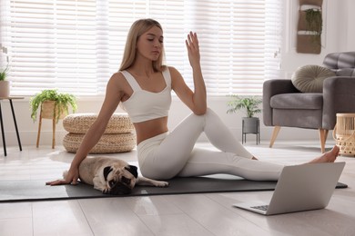 Photo of Beautiful woman with dog following online yoga class at home