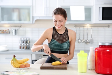 Photo of Young woman preparing protein shake at table in kitchen