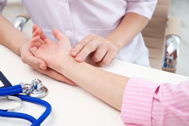 Doctor checking little girl's pulse in hospital