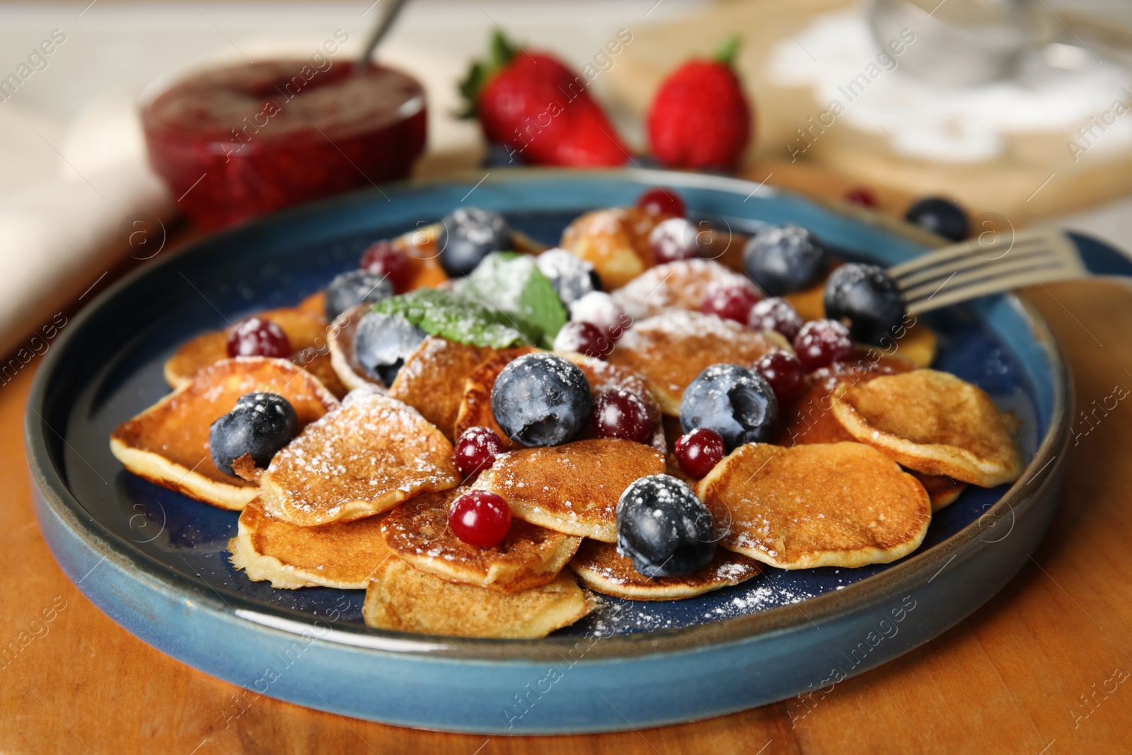 Photo of Cereal pancakes with berries on wooden board, closeup