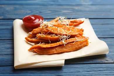 Tasty sweet potato fries on wooden background