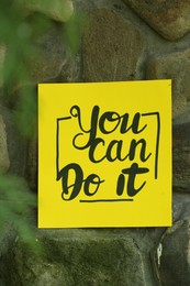 Photo of Yellow paper note with phrase You Can Do It on stone background