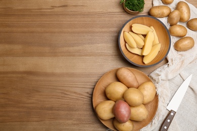 Flat lay composition with fresh organic potatoes and space for text on wooden background