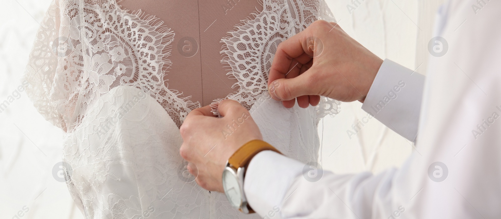 Image of Dressmaker working with wedding dress on mannequin in workshop, closeup. Banner design