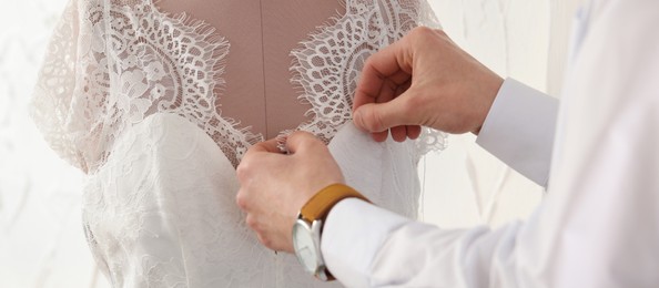 Image of Dressmaker working with wedding dress on mannequin in workshop, closeup. Banner design
