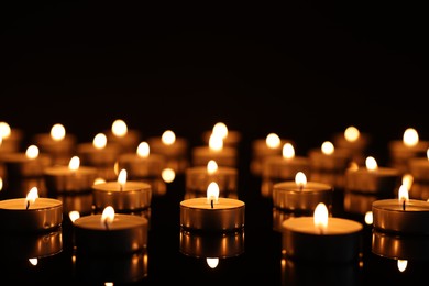 Photo of Burning candles on mirror surface in darkness