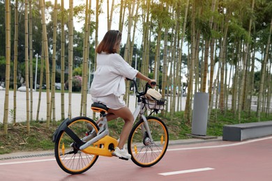 Photo of Beautiful young woman riding bicycle on lane in city
