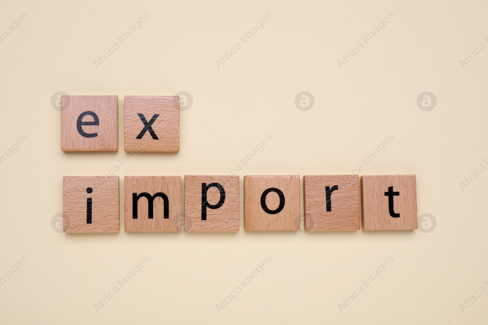 Photo of Words Export and Import made of wooden squares on beige background, top view