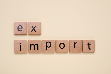 Photo of Words Export and Import made of wooden squares on beige background, top view