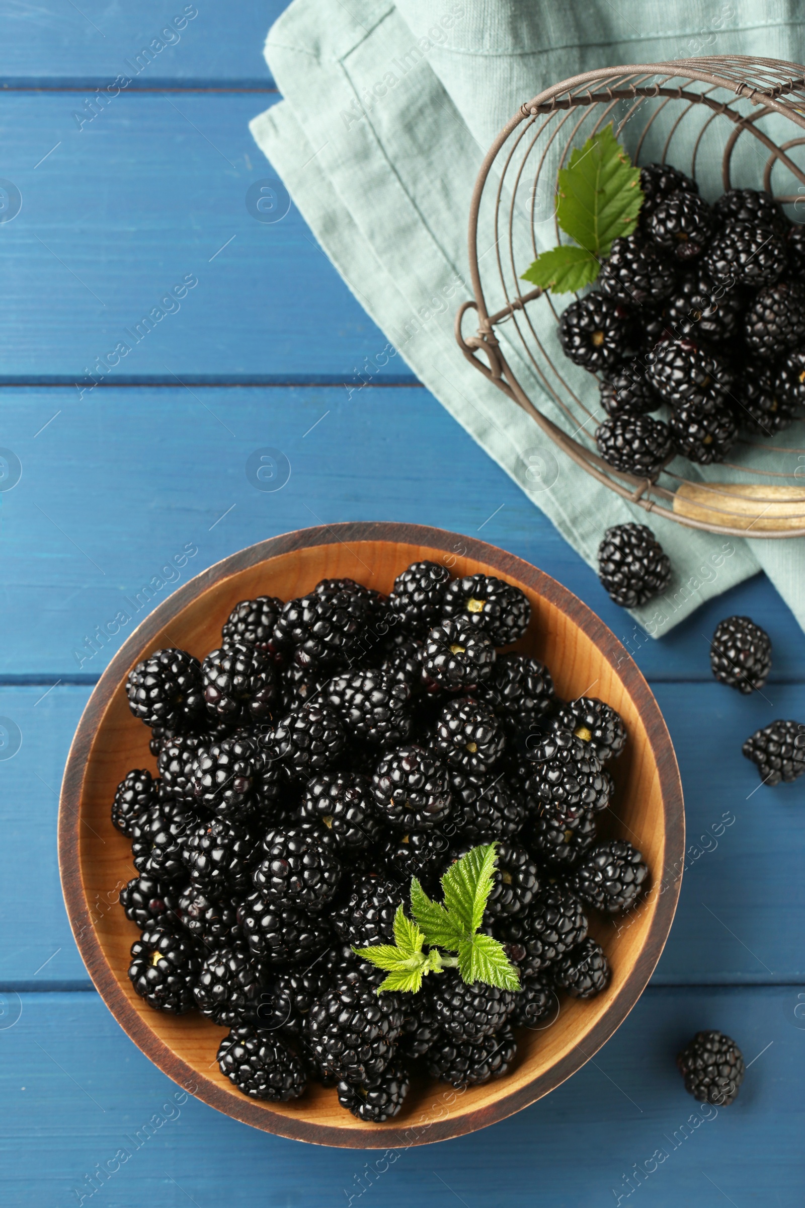Photo of Fresh ripe blackberries on blue wooden table, flat lay