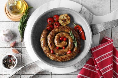 Delicious homemade sausage with garlic, tomatoes, rosemary and chili served on light tiled table, flat lay