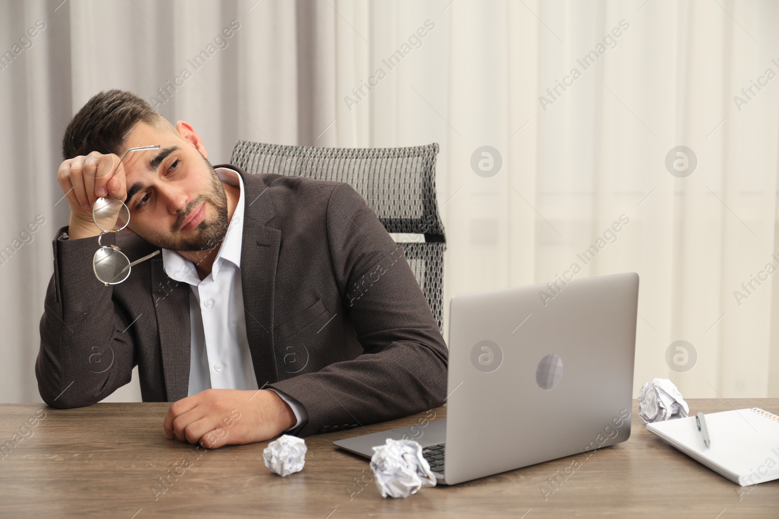 Photo of Tired sad businessman sitting at table in office