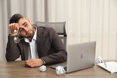 Photo of Tired sad businessman sitting at table in office