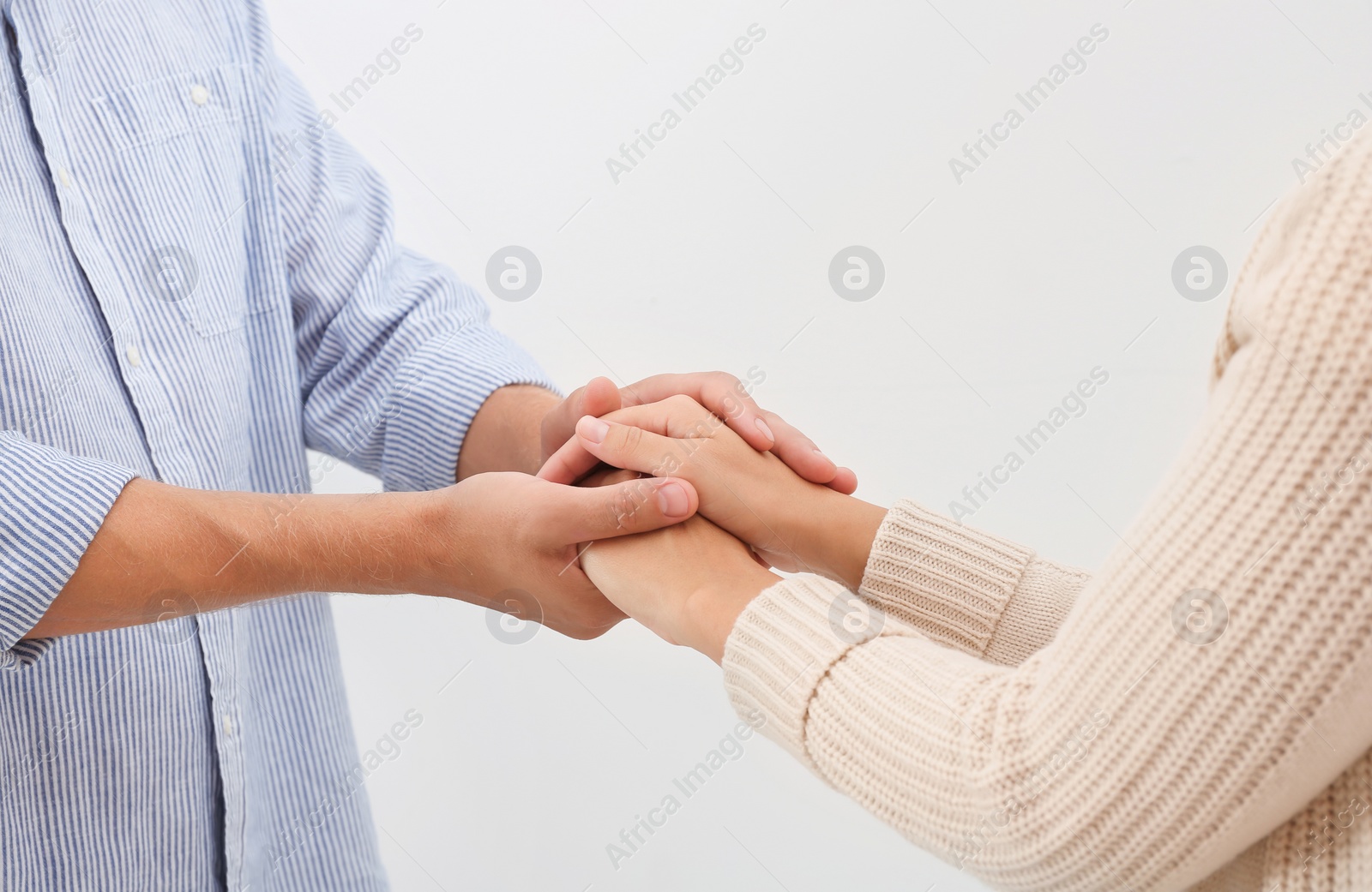 Photo of Man holding woman's hands on light background. Concept of support and help