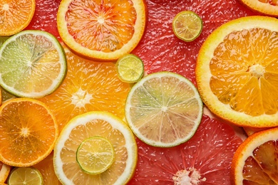 Photo of Slices of fresh citrus fruits as background, top view