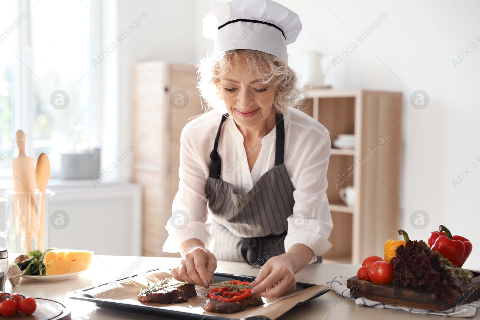 Photo of Professional female chef preparing meat on table in kitchen