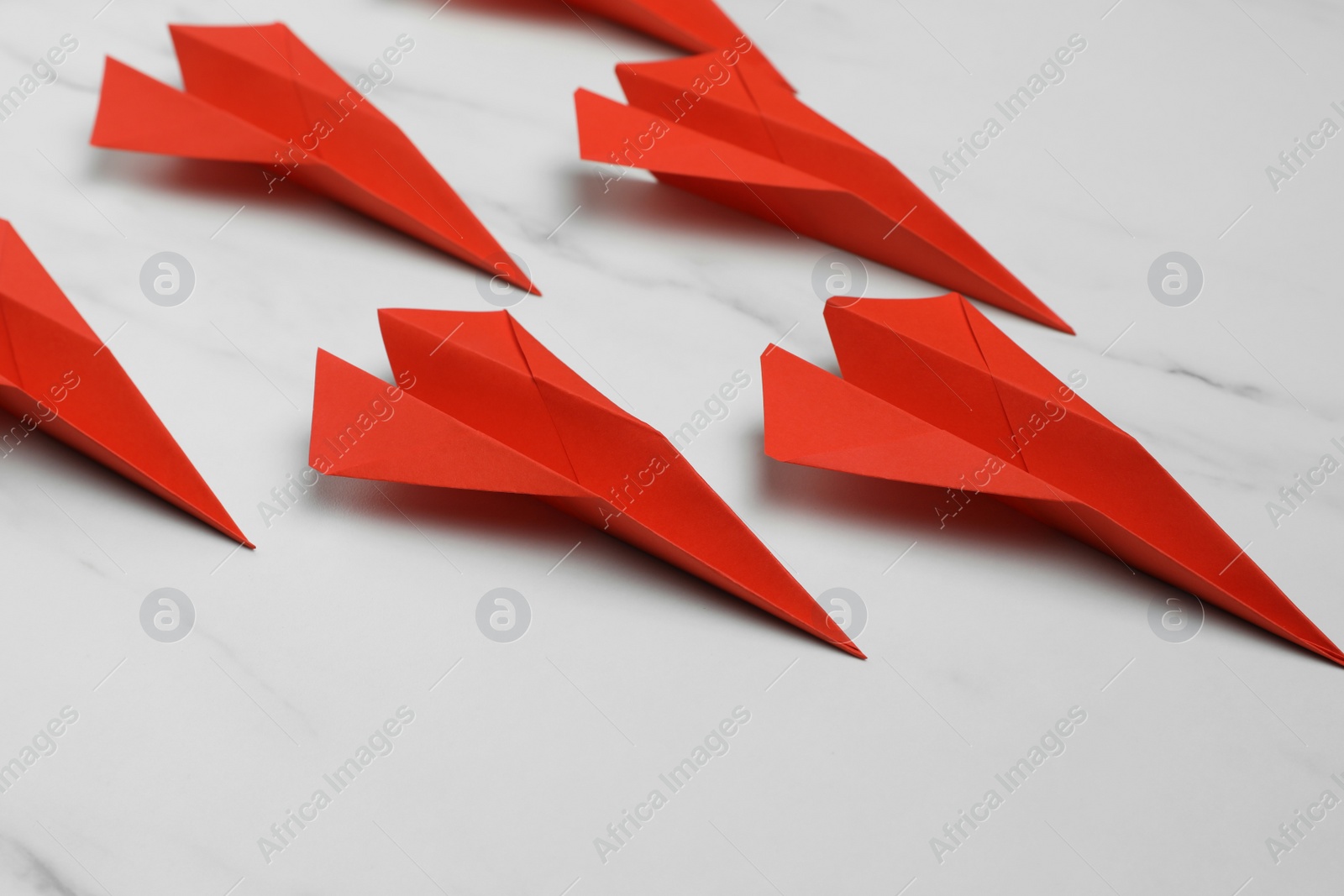 Photo of Many handmade paper planes on white marble table, closeup