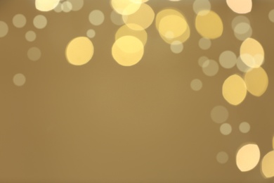 Photo of Beautiful blurred lights on beige background, bokeh effect. Space for text