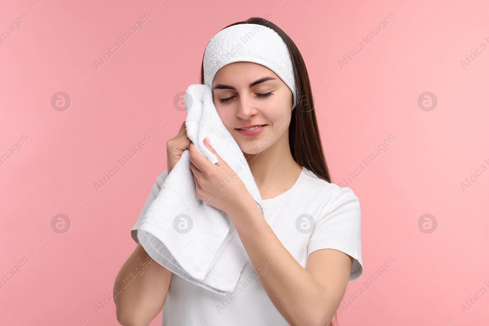 Photo of Washing face. Young woman with headband and towel on pink background