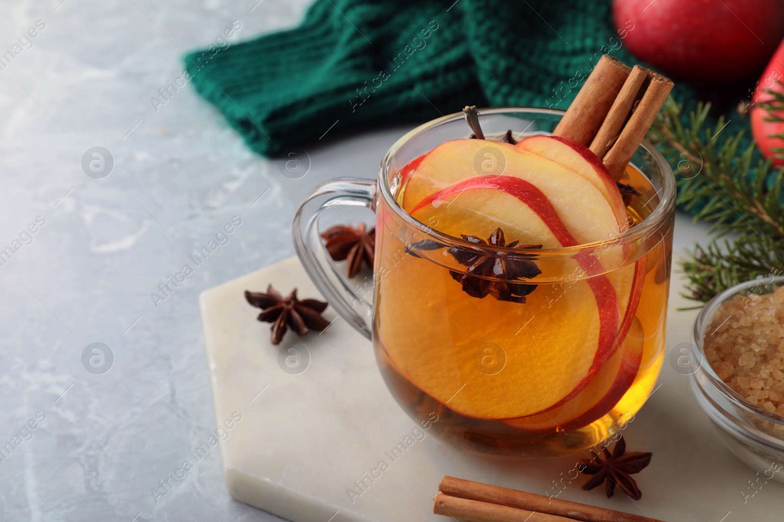 Photo of Aromatic hot mulled cider on light grey marble table. Space for text