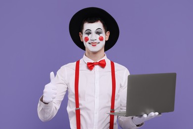 Photo of Funny mime artist with laptop showing thumbs up on purple background