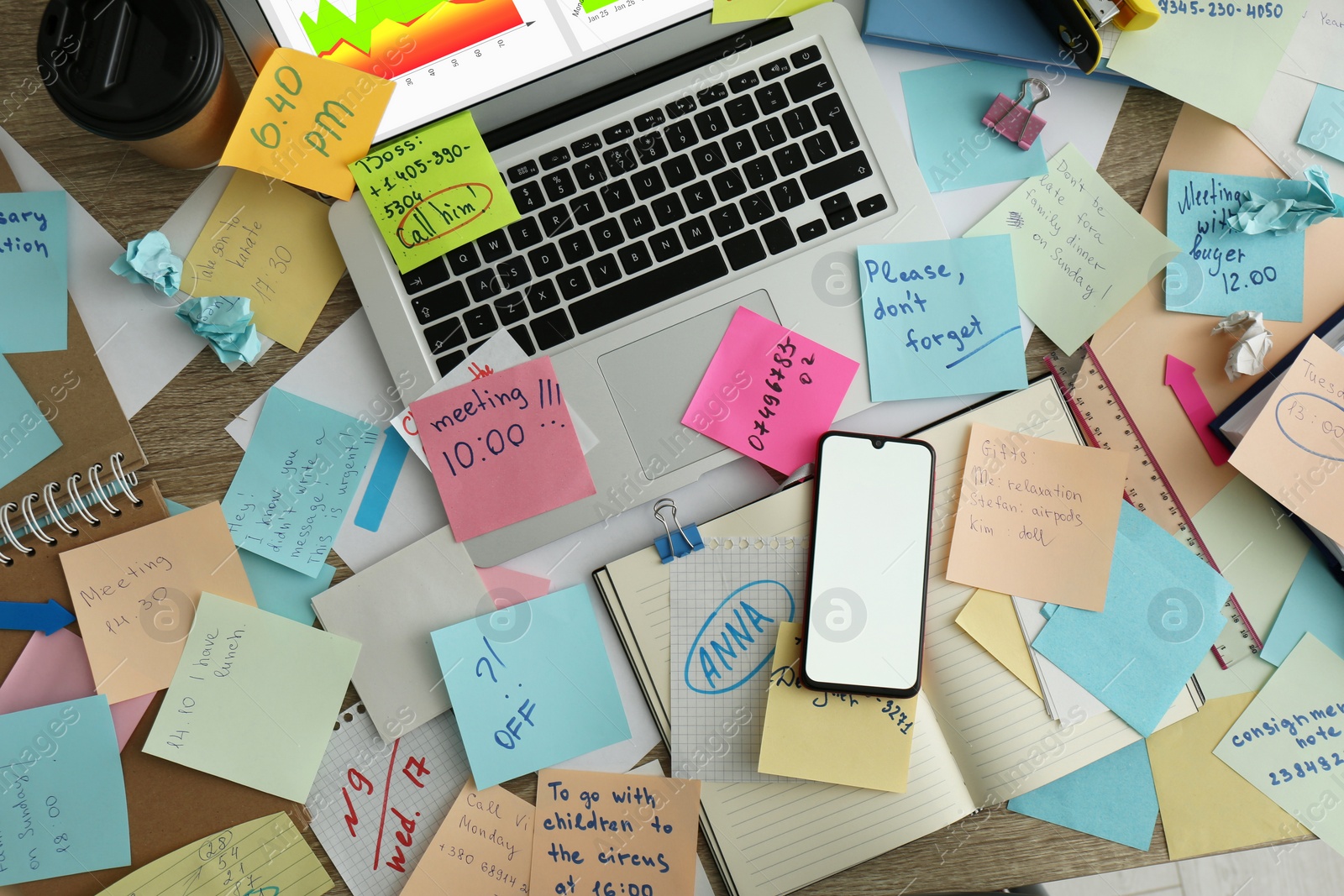 Photo of Laptop, smartphone, notes and office stationery in mess on desk, top view. Overwhelmed with work