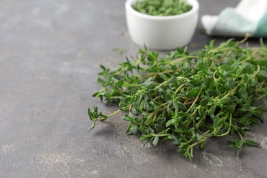 Photo of Bunch of aromatic thyme on grey table, closeup. Space for text