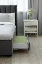 Storage drawer with bedding under comfortable bed in room