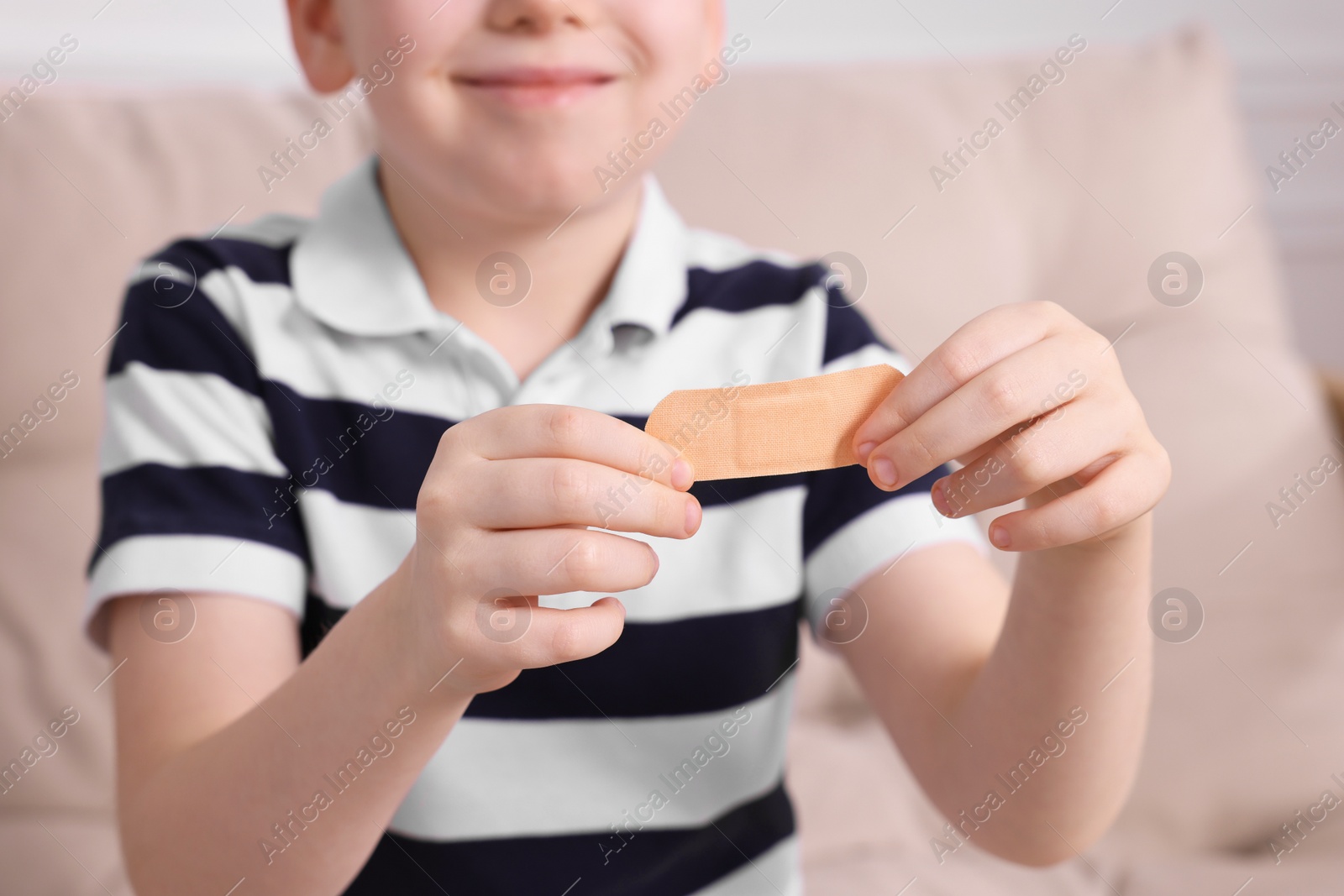 Photo of Little boy with sticking tape on sofa, closeup