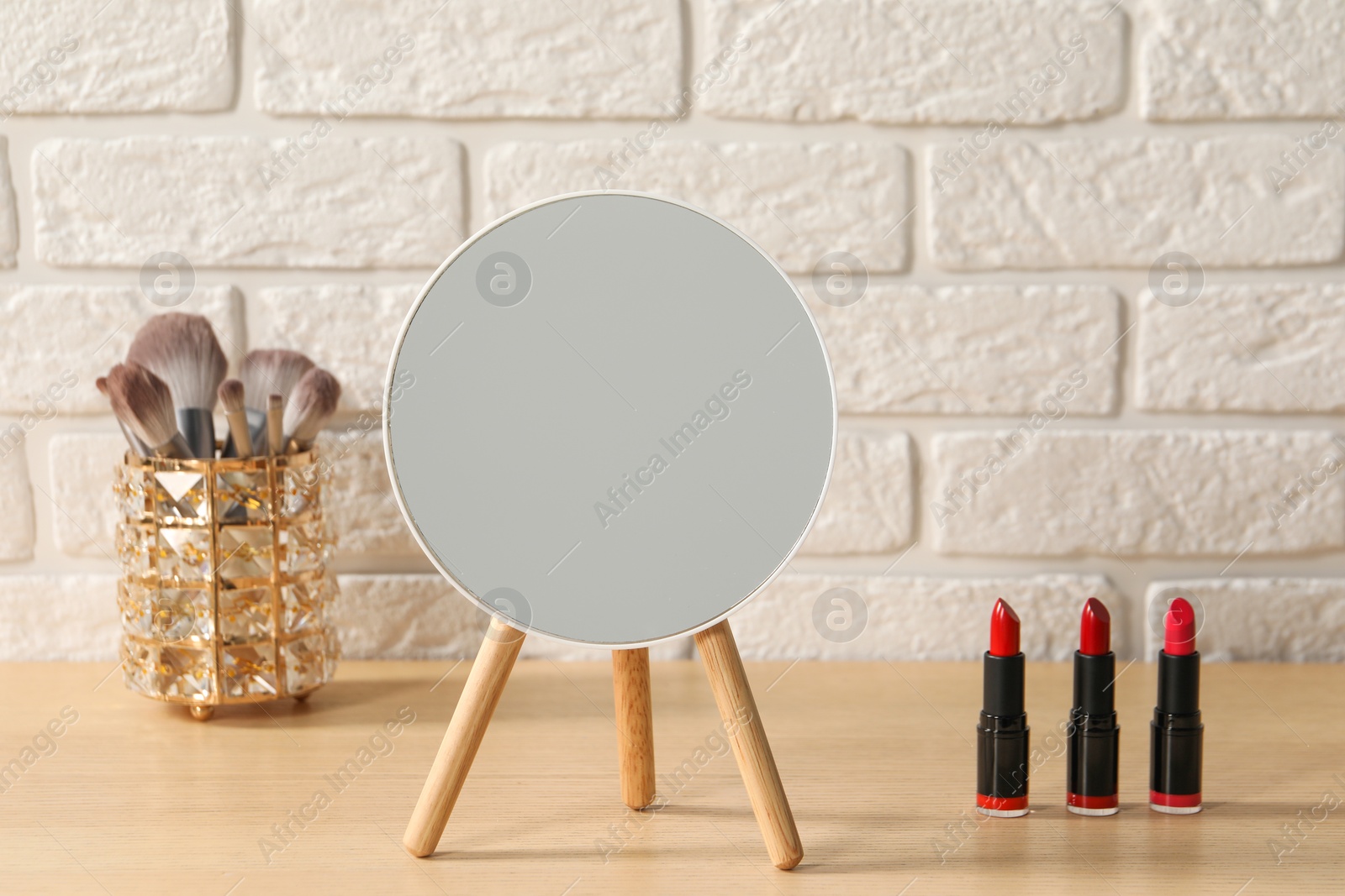 Photo of Mirror and makeup products on wooden dressing table in room