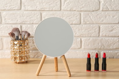 Mirror and makeup products on wooden dressing table in room