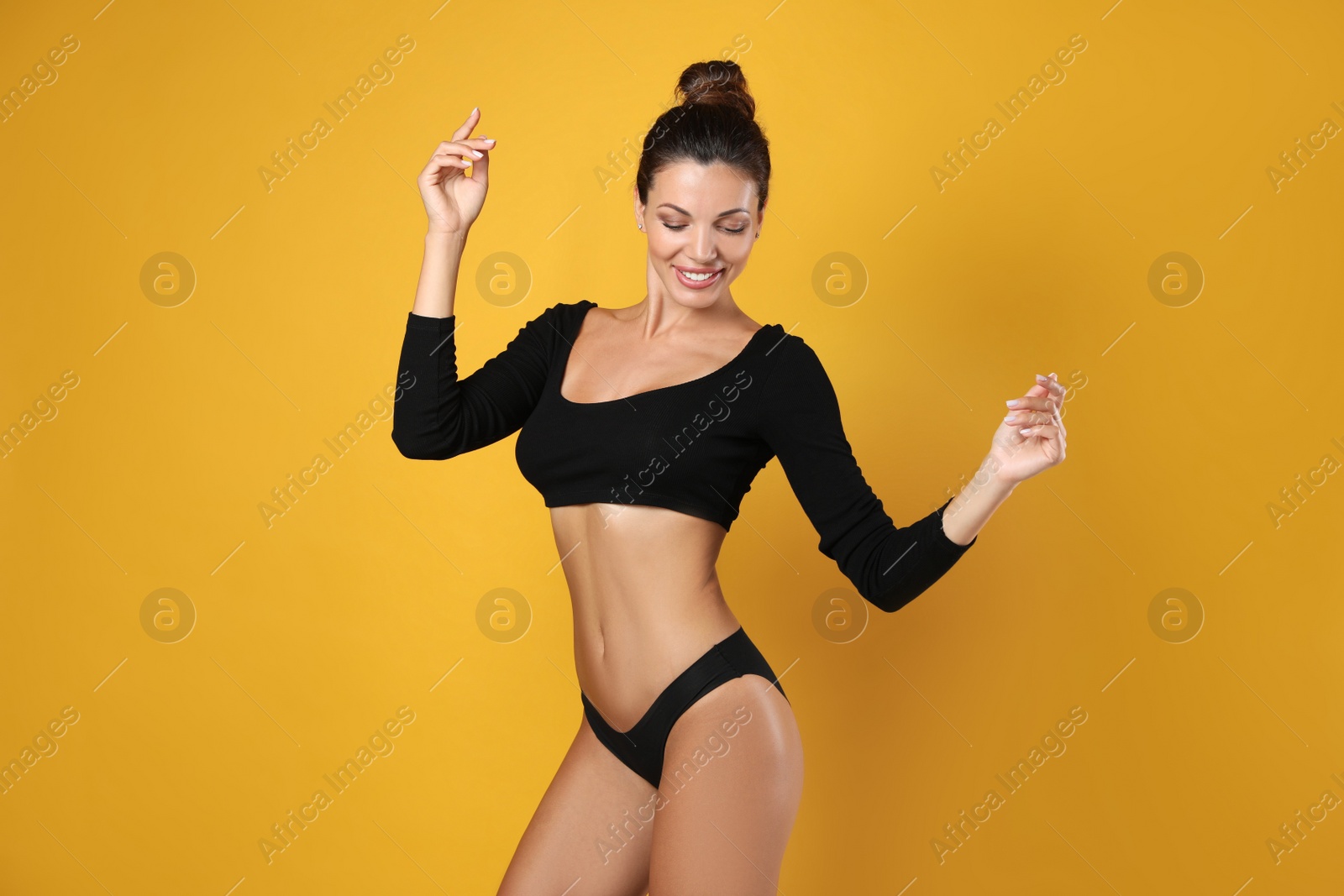 Photo of Beautiful woman in black sexy panties on yellow background